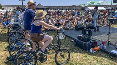 La artista Madi Diaz (derecha) se presenta en el Festival Folk de Newport en un escenario alimentado con electricidad generada por los asistentes en bicicletas fijas (a la izquierda) el viernes 22 de julio de 2022, en Newport, Rhode Island.