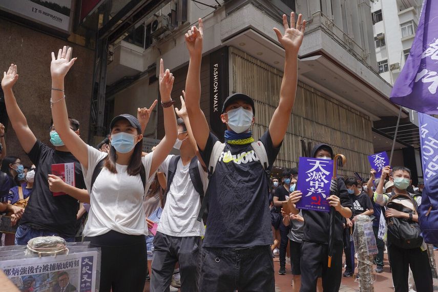 Manifestantes alzando las manos en un gesto que significa Cinco demandas, ni una menos mientras marchan por una calle del centro de Hong Kong en una protesta a favor de la democracia y contra una ley de seguridad nacional, el domingo 24 de mayo de 2020.&nbsp;