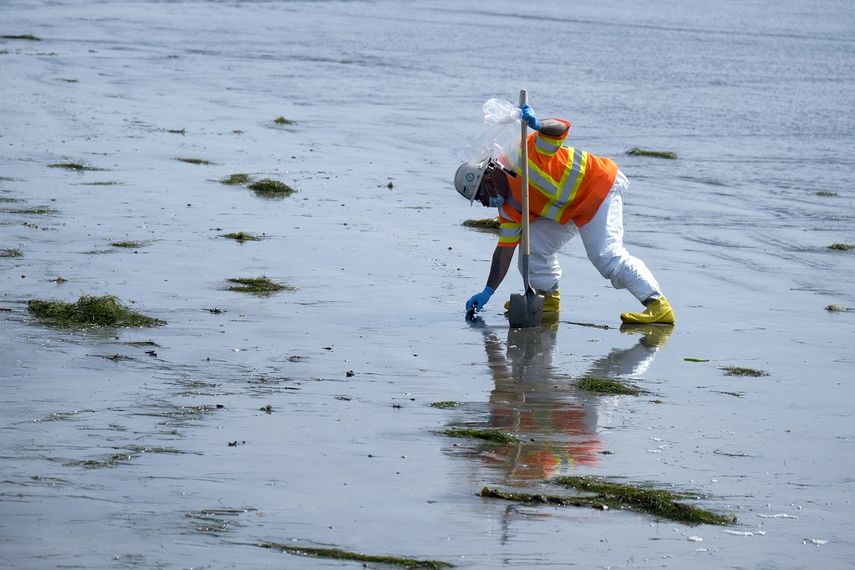 Un operario, con un traje de protección, limpia una playa contaminada tras un vertido de petróleo, en Newport Beach, California, el 6 de octubre de 2021.&nbsp;