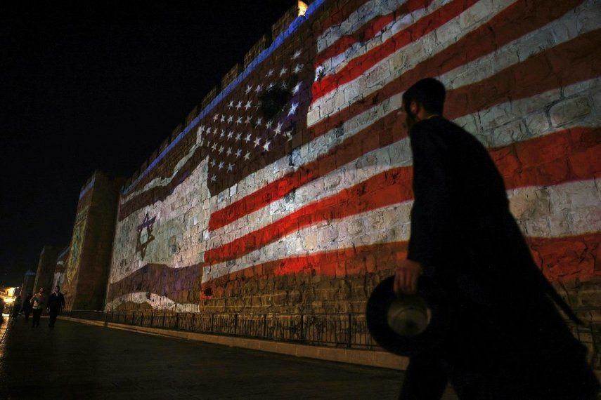La gente pasa junto a una proyección que representa las banderas israelí y estadounidense en los muros de la Ciudad Vieja de Jerusalén el 22 de junio de 2025.&nbsp;&nbsp;
