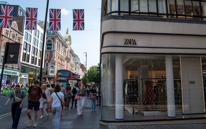 Los compradores pasan bajo banderas de la Unión Europea al pasar frente a una tienda de ropa Zara en el centro de Londres el 6 de agosto de 2025.