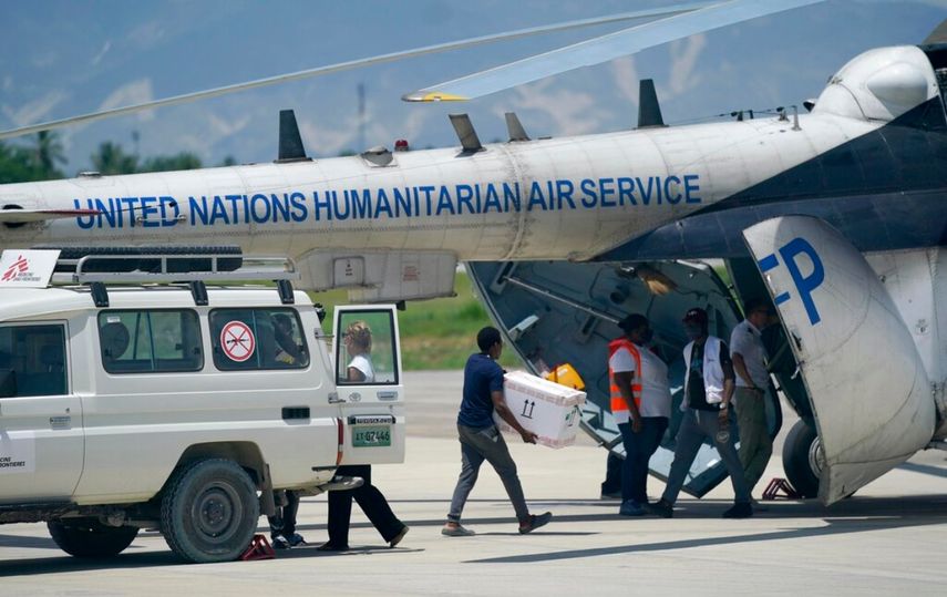 Personas cargan suministros de emergencia de una ambulancia de Médicos sin Fronteras en un helicóptero de las Naciones Unidas con destino a la ciudad de Les Cayes, devastada por el terremoto, en la terminal local del aeropuerto Toussaint Louverture en Puerto Príncipe, Haití.