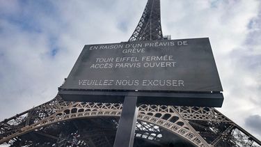 Una fotografía tomada a través de un panel de vidrio muestra un cartel digital que muestra un mensaje que dice Debido a una huelga, la Torre Eiffel está cerrada, la Explanada está abierta, nos disculpamos en la Torre Eiffel de París el 7 de marzo de 2023, durante un día de huelgas a nivel nacional y protestas convocadas por sindicatos por la reforma de las pensiones propuesta por el gobierno. La Torre Eiffel estará cerrada al público el 27 de diciembre de 2023 debido a una huelga.  