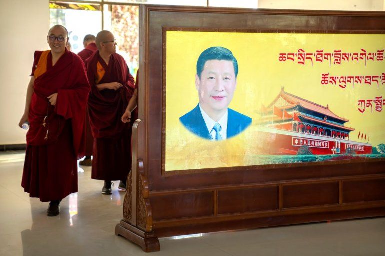 Varios monjes pasan junto a un retrato del presidente chino Xi Jinping y la plaza Tiananmén de Beijing en el Colegio Budista Tibetano.