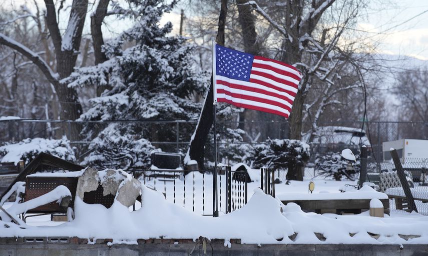 Una bandera de Estados Unidos ondea sobre los restos calcinados de una casa destruida por incendios forestales, el jueves 6 de enero de 2022, en Superior, Colorado.&nbsp;
