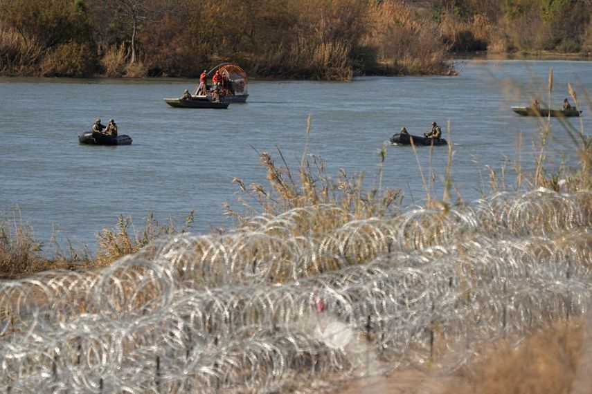 Guardas que patrullan el río Bravo en pequeñas embarcaciones pasan junto a filas de alambre con concertinas, instaladas para ayudar a frenar los cruces ilegales, el 1 de febrero de 2024, en Eagle Pass, Texas.&nbsp;