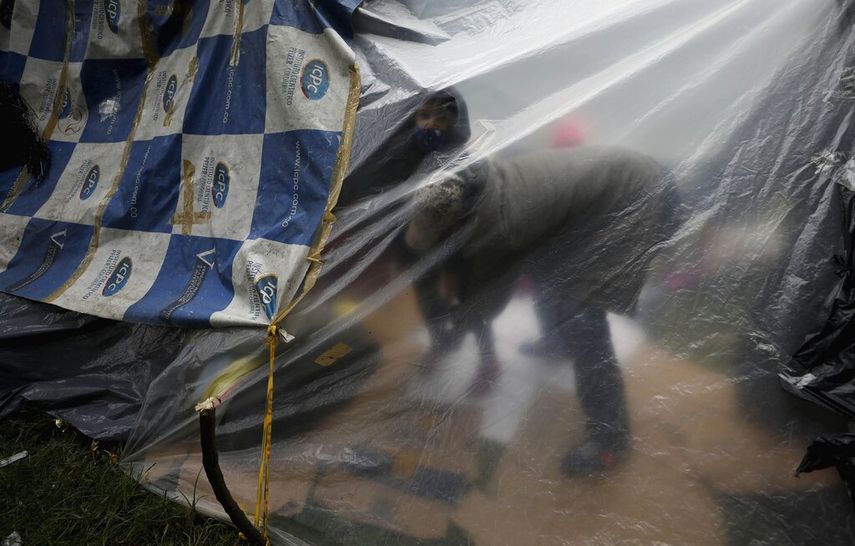 Un inmigrante venezolano desempleado y sin hogar viste a su hijo dentro de una carpa cerca de la terminal principal de autobuses en Bogot&aacute;, Colombia, el mi&eacute;rcoles 3 de junio de 2020. Frente a las restricciones de viaje y sin trabajo debido al cierre econ&oacute;mico para frenar al COVID-19, los migrantes venezolanos acampan a la espera de ayuda para volver a su pa&iacute;s.
