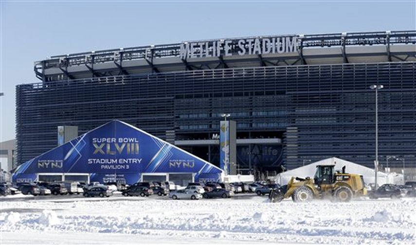 Un vehículo equipado con pala mecánica retira la nieve del estacionamiento del estadio MetLife Stadium cerca de uno de los accesos a la sede del Super Bowl XLVIII. (AP)