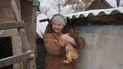 Olga, una de las 16 residentes que todavía viven en una aldea en el frente, carga un conejo mientras habla con periodistas en el patio de su casa no lejos del frente en la región de Luhansk, en el este de Ucrania, el viernes 28 de enero de 2022.