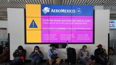 Trabajadores mexicanos que tienen vuelos de Aeroméxico a Canadá esperan bajo un tablero de información en el Aeropuerto Internacional Benito Juárez en la Ciudad de México, el viernes 7 de enero de 2022.&nbsp;