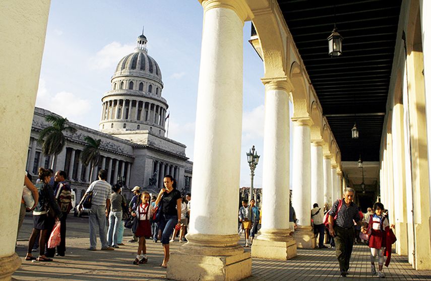 Varias personas pasan por una calle donde se puede ver el Capitolio de La Habana (EFE)