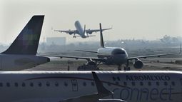 Un avión de pasajeros despega del Aeropuerto Internacional Benito Juárez el 12 de mayo de 2022 en la Ciudad de México, mientras otros aviones se desplazan en la pista.