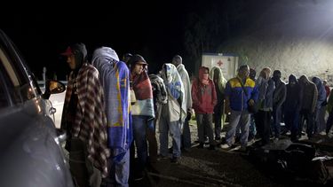 Fotograía del 31 de agosto de 2018 de un grupo de migrantes venezolanos en fila para recibir pan y café donado por una familia que les atiende desde su auto, en una gasolinera de Pamplona, Colombia.