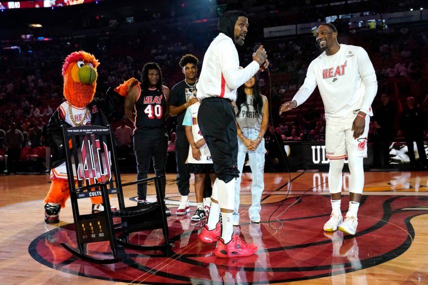 El alero del Heat de Miami, Udonis Haslem, a la izquierda, con el centro Bam Adebayo, a la derecha, mientras le presentan una mecedora durante una ceremonia antes de un partido de baloncesto de la NBA contra el Orlando Magic, el domingo 9 de abril de 2023 en Miami.