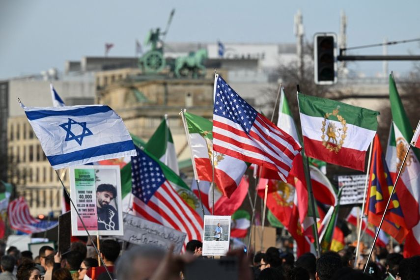 Los manifestantes ondean la bandera iraní de la revolución preislámica de 1979 y las banderas nacionales de Israel y de los Estados Unidos durante una manifestación Libertad para Irán mientras se ve la cuadriga en la parte superior de la Puerta de Brandeburgo al fondo en Berlín, Alemania, el 28 de febrero de 2026.
