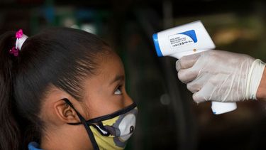 Un trabajador de la salud toma la temperatura de una niña para ayudar a aplanar la curva de contagios del nuevo coronavirus en el mercado Central de Abastos en Ciudad de México el jueves 18 de junio de 2020.