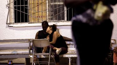 En esta foto del 28 de julio de 2019, una mujer de Nicaragua abraza a un hombre de &Aacute;frica bajo los focos del patio en el refugio El Buen Pastor para migrantes en Ciudad Ju&aacute;rez, M&eacute;xico