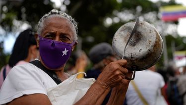 Una manifestante golpea una olla para referirse al hambre durante una manifestación de trabajadores públicos activos y jubilados, incluidos maestros, que exigen mejores salarios y el resto de su bono de vacaciones que dicen fue pagado parcialmente, mientras marchan hacia el Ministerio de Trabajo en Caracas, Venezuela, el martes 2 de agosto de 2022.