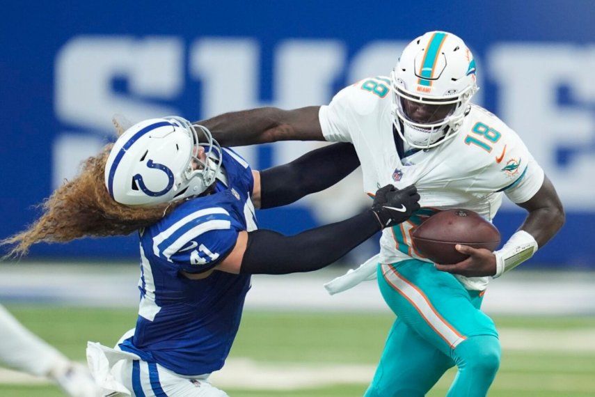 El mariscal de campo de los Miami Dolphins, Tyler Huntley (18) bloquea una entrada del apoyador de los Indianapolis Colts, Grant Stuard (41) mientras corre el balón durante la primera mitad de un juego de fútbol de la NFL, el domingo 20 de octubre de 2024 en Indianápolis.&nbsp;