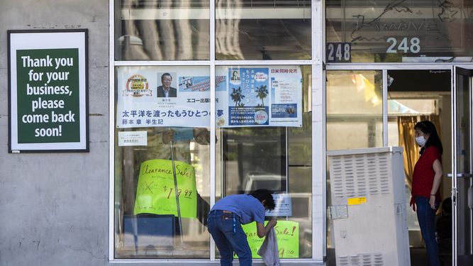 Una pareja limpia el escaparate de su tienda en el barrio Little Tokyo de Los &Aacute;ngeles.