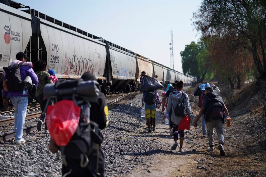 Migrantes caminan junto a un tren con dirección al norte, esperando poder subirse a él, en Huehuetoca, México, el viernes 12 de mayo de 2023.