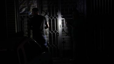 Un hombre cierra una puerta en la oscuridad por la falta de fluido eléctrico en Caracas, Venezuela.&nbsp;