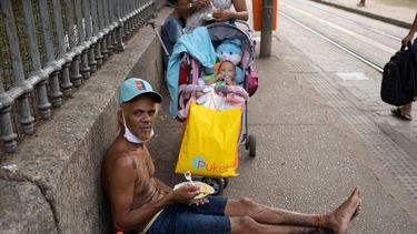 Un hombre mira a la cámara mientras come el almuerzo donado por la Fundación Leao XIII durante la pandemia de COVID-19, el miércoles 7 de abril de 2021, en Río de Janeiro, Brasil.