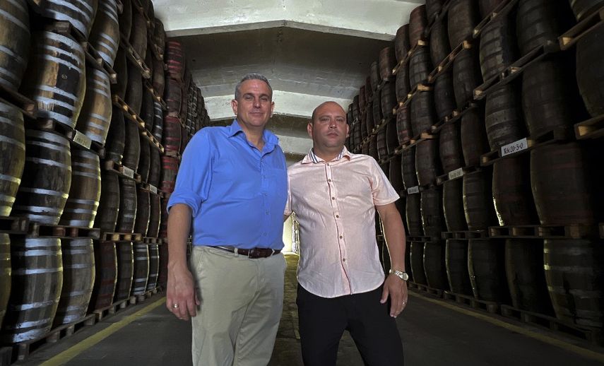 El maestro ronero cubano César Martí y su aprendiz Mitehel Niebla posan para una fotografía en el sótano de la Fábrica Central de Ron en la ciudad de Santo Domingo, provincia de Villa Clara, a unos 270 kilómetros al sureste de La Habana, Cuba, el 8 de marzo de 2019.