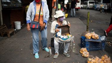   Vendedores callejeros usan mascarillas para protegerse del nuevo coronavirus mientras esperan clientes en Caracas, Venezuela, el martes 21 de abril de 2020.   