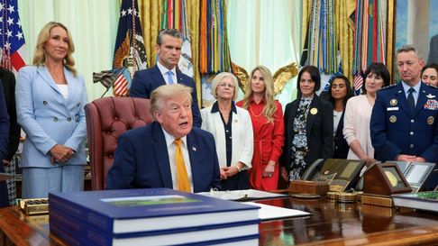 El presidente Donald Trump (sentado) se prepara para firmar una orden ejecutiva que crea la Comisión de Cónyuges Militares en el Despacho Oval de la Casa Blanca, el 3 de agosto de 2026, en Washington, DC.