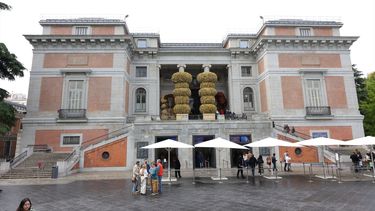 Varias personas esperan para entrar en el Museo Nacional del Prado que transformó su fachada clásica en una monumental portada barroca el 20 de mayo de 2023, en Madrid. La intervención artística, en colaboración con El Corte Inglés, fue con motivo del Día Internacional de los Museos.