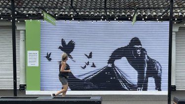 Una corredora pasa frente a una reproducción de un mural de Banksy afuera del Zoológico de Londres, el domingo 18 de agosto de 2024.&nbsp;