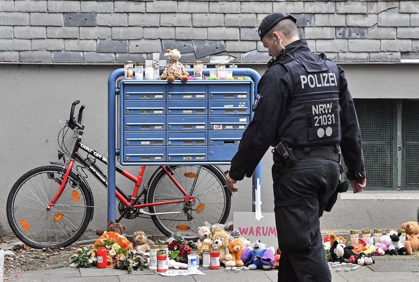 Un policía pasa frente a velas y osos de peluche en la entrada de una casa en donde cinco niños fueron encontrados muertos en Solingen, Alemania, el viernes 4 de septiembre de 2020.&nbsp;