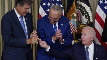 El presidente Joe Biden ofrece un lapicero al senador demócrata Joe Manchin durante una cena en la Casa Blanca. En el centro el jefe de la mayoría demócrata en el Senado, Chuck Shumer. Agosto de 2022.