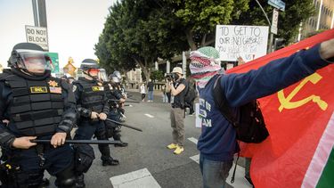 Un manifestante con una keffiyeh multicolor ondea la bandera de la Unión Soviética mientras los manifestantes se enfrentan con las fuerzas del orden en las calles que rodean el edificio federal durante una protesta tras los operativos federales de inmigración en Los Ángeles, California, el 8 de junio de 2025.&nbsp;