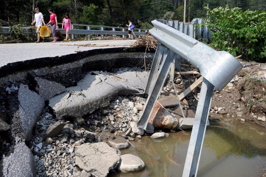 Varias personas caminan por un puente dañado por inundaciones, el martes 11 de julio de 2023, en Ludlow, Vermont.