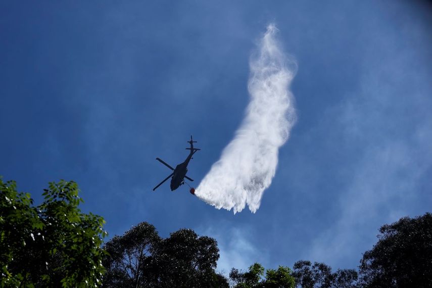 Un helicóptero rocía agua sobre un incendio forestal en las montañas que rodean Bogotá, Colombia, el martes 23 de enero de 2024