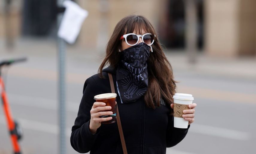 &nbsp; Una mujer con tapabocas lleva dos caf&eacute;s que acaba de comprar en una cafeter&iacute;a de Denver, que lentamiente empieza a reabrir sus negocios, el 13 de mayo del 2020. A medida que se vuelve a la normalidad tras las cuarentenas por el coronavirus, la gente tiene que decidir si vale la pena exponerse a contraer el virus, que sigue dando vueltas, o es preferible permanecer m&aacute;s tiepo en casa.&nbsp;