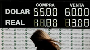 En esta foto de archivo del 12 de agosto de 2019, una mujer camina frente a un tablero que muestra el tipo de cambio en Buenos Aires, Argentina