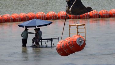 Trabajadores toman un descanso de colocar boyas para que sean utilizadas como barrera fronteriza en el río Bravo, el miércoles 12 de julio de 2023, a la altura de Eagle Pass, Texas.