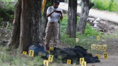 En México no para la violencia, un policía de la Fiscalía General fotografía cuerpos de policías asesinados en Guerrero.