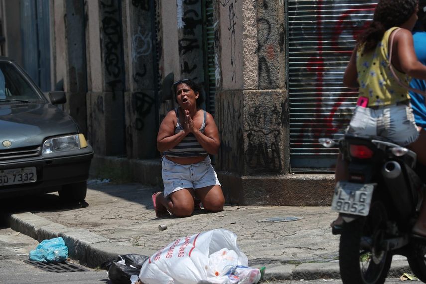 &nbsp;Una mujer se arrodilla con miedo en medio de un operativo policial que resultó en un tiroteo, en Río de Janeiro (Brasil)