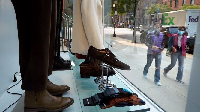 Dos personas pasan frente a una vidriera de una tienda minorista.