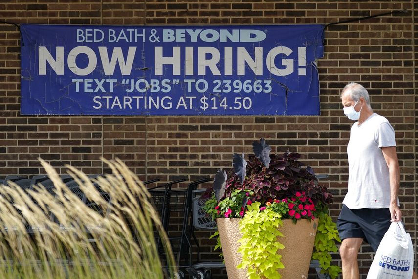 Una persona pasa frente a un letrero de búsqueda de empleo.