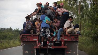 En esta fotografía de archivo del 2 de octubre de 2020, los migrantes viajan en la parte trasera de un camión de carga que redujo la velocidad para darles la oportunidad de subirse a los migrantes en su trayectoria.&nbsp;