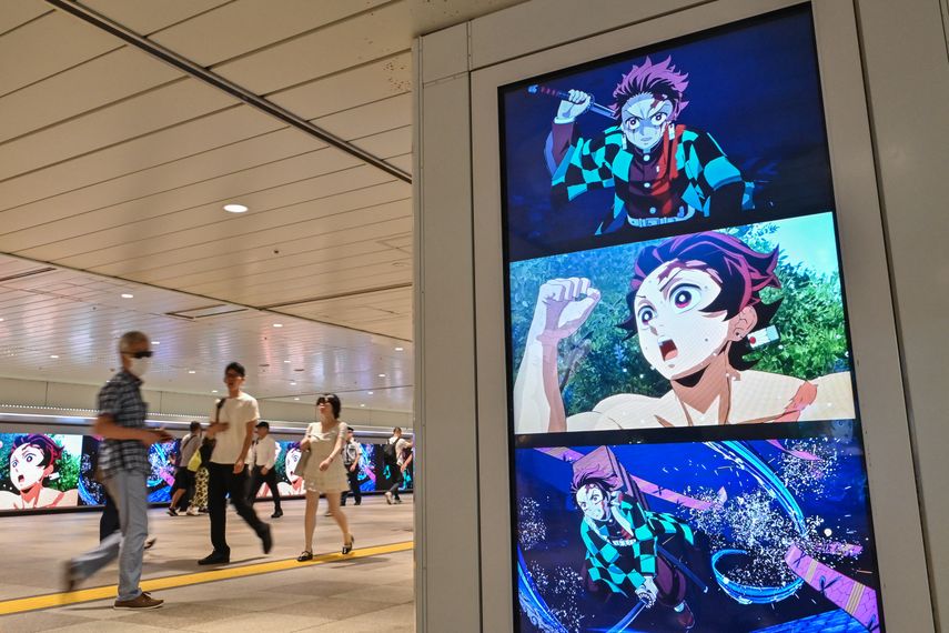 Varias personas caminan junto a vallas publicitarias digitales que anuncian el próximo lanzamiento del videojuego Demon Slayer: Kimetsu no Yaiba – The Hinokami Chronicles 2, a lo largo de un pasillo dentro de una estación de tren en el centro de Tokio el 29 de julio de 2025.