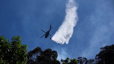 Un helicóptero rocía agua sobre un incendio forestal en las montañas que rodean Bogotá, Colombia, el martes 23 de enero de 2024