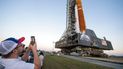 Los invitados y los empleados de la NASA toman fotos mientras el cohete del Sistema de Lanzamiento Espacial (SLS) de la NASA con la nave espacial Orion a bordo sale de High Bay 3 del edificio de ensamblaje de vehículos por primera vez, en el Centro Espacial Kennedy en Cabo Cañaveral, Florida.