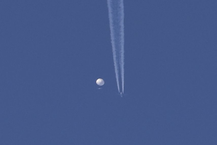 En esta foto proporcionada por Brian Branch, un gran globo se desplaza por encima de la zona de Kingstown, Carolina del Norte, mientras por debajo se observa un avión y la estela que deja a su paso. 