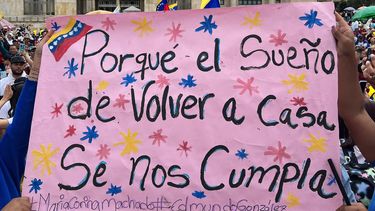 Venezolanos muestran pancarta durante acto de campaña de la oposición venezolana en Bogotá, Colombia.